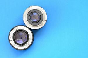 Two photographic lenses lie on a bright blue background. Space for text photo