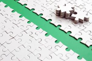 The green path is laid on the platform of a white folded jigsaw puzzle. The missing elements of the puzzle are stacked nearby. Texture image with space for text photo