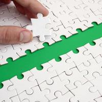 The human hand paves the way to the surface of the jigsaw puzzle, forming a green space. The concept of overcoming the difficulties on the way to success photo