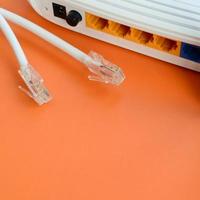 Internet router and Internet cable plugs lie on a bright orange background. Items required for Internet connection photo