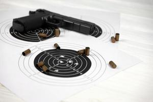 pistola y muchas balas disparando objetivos en la mesa blanca en el polígono de campo de tiro. entrenamiento para apuntar y disparar foto
