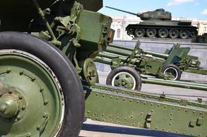 Photo of three guns of the Soviet Union of the Second World War against the background of the green tank T-34