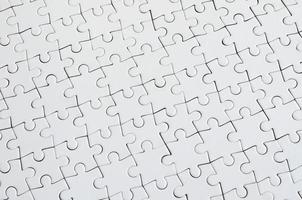 Close up texture of a white jigsaw puzzle in assembled condition. Top view. Many components of a large whole mosaic are united photo