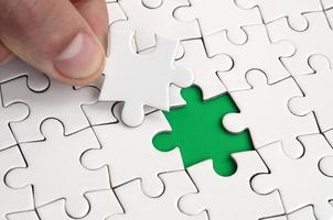 The human hand fills the last missing elements of the surface from the jigsaw puzzle. The concept of the completion of the initiated cases photo