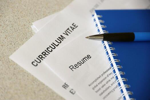 Top view of stack of office documents including resume and cv forms on the desk close to pen and notepad. Job seeking process. Hunting for workplace photo