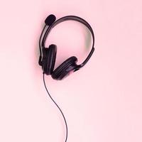 Music listening concept. Black headphones lies on pink background photo