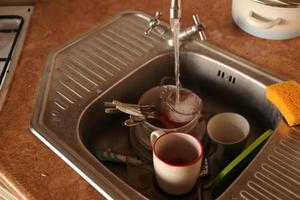 Stack of dirty dishes with food leftovers in the kitchen sink. Unwashed dishes photo