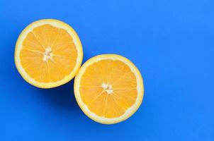 Top view of a several orange fruit slices on bright background in blue color. A saturated citrus texture image photo