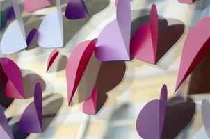 A lot of pink, purple and white paper hearts decorate the window of the house photo