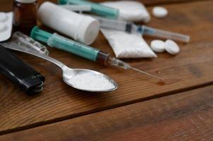 A lot of narcotic substances and devices for the preparation of drugs lie on an old wooden table photo