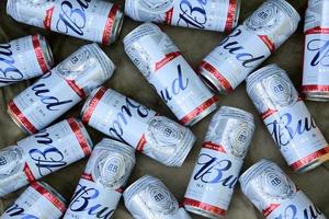 KHARKOV, UKRAINE - JULY 2, 2021 Many Cans of Budweiser Lager Alcohol Beer lies on camo surface. Budweiser is Brand from Anheuser-Busch Inbev most popular in America photo