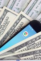 KHARKOV, UKRAINE - JULY 2, 2021 Smartphone screen with Google chrome app and lot of hundred dollar bills. Business and social networking concept photo
