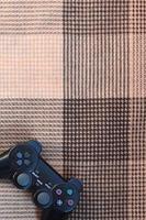 Video game controller lies on a checkered plaid photo