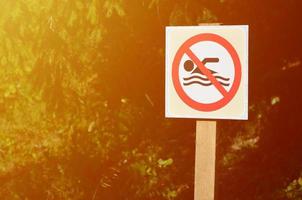 A pillar with a sign denoting a ban on swimming. The sign shows a crossed-out floating person photo