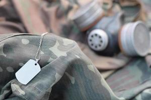 Dog tag with stalker soldiers soviet gas mask lies on green khaki camouflage jackets photo
