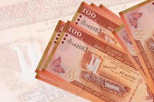 Los billetes de 100 rupias de Sri Lanka se encuentran apilados en el fondo de un gran billete semitransparente. presentación abstracta de la moneda nacional foto