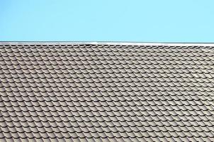 A fragment of a roof from a metal tile of dark red color. Quality Roofing photo