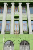 Restored old multi-storey building with antique columns, painted in green photo