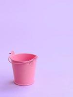 un cubo rosa vacío en miniatura se encuentra sobre un fondo violeta pastel. concepto mínimo foto