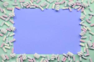 Colorful marshmallow laid out on green and lilac paper background photo