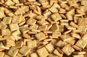 Background texture of small edible squares baked from dough and sprinkled with salt. A lot of salt cracker photo