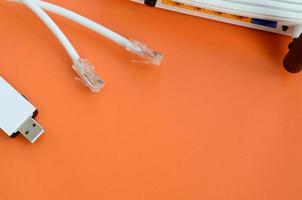 el enrutador de Internet, el adaptador wi-fi usb portátil y los enchufes del cable de Internet se encuentran sobre un fondo naranja brillante. elementos necesarios para la conexión a internet foto