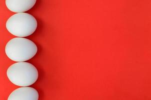 A few white eggs on a bright red background photo