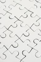 Close up of a white jigsaw puzzle in assembled state in perspective. Many components of a large whole mosaic are united photo
