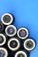 Several photographic lenses lie on a bright blue background. Space for text photo