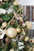 A beautiful decorated Christmas tree on the background of a bookshelf with many books of different colors. Christmas background image of the library photo