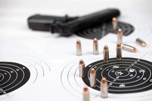 Gun and many bullets shooting targets on white table in shooting range polygon. Training for aiming and shooting photo