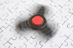 A wooden spinner spins on a white jigsaw puzzle background photo
