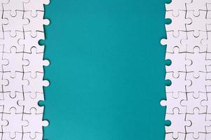 Fragment of a folded white jigsaw puzzle on the background of a blue plastic surface. Texture photo with copy space for text