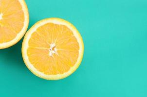 Top view of a several orange fruit slices on bright background in turquoise green color. A saturated citrus texture image photo