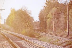 Autumn industrial landscape. Railway receding into the distance among green and yellow autumn trees photo