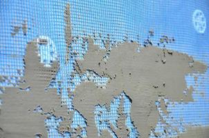 The texture of the wall, covered with gray foam polystyrene plates, covered with a blue reinforcing mesh and covered with a mixture for gluing it. Stage of wall insulation photo