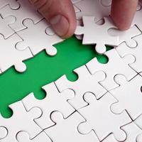 The human hand paves the way to the surface of the jigsaw puzzle, forming a green space. The concept of overcoming the difficulties on the way to success photo