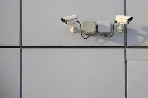 White surveillance camera built into the metal wall of the office building photo