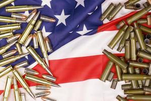 Many yellow 9mm and 5.56mm bullets and cartridges on United States flag. Concept of gun trafficking on USA territory or shooting range photo