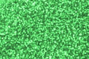 Blurred green decorative sequins. Background image with shiny bokeh lights from small elements photo