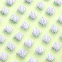Colorful marshmallow laid out on lime paper background. pastel creative textured pattern photo