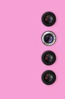 A few camera lenses with a closed aperture lie on texture background of fashion pastel pink color paper in minimal concept. Abstract trendy pattern photo