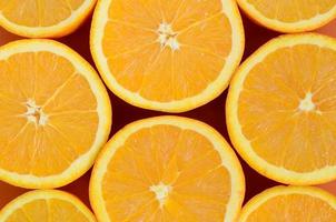 Top view of a several orange fruit slices on bright background in orange color. A saturated citrus texture image photo