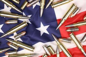 Many yellow 9mm and 5.56mm bullets and cartridges on United States flag. Concept of gun trafficking on USA territory or special ops photo