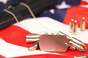 Many yellow 9mm bullets and gun with dogtags on United States flag. Concept of duty and service in US army forces photo