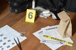 Evidence Chain of Custody Labels and brown paper bag with fingerprints applicant card lies against big heroin packets and packs of money bills as evidence in crime scene investigation process photo