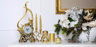 New Year and Christmas composition. Decorative golden clock, thick candles, candlestick, pot of flowers and framed canvas that hangs on the wall photo