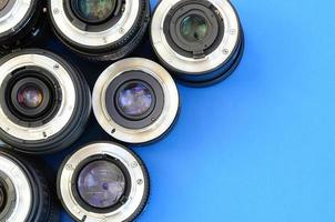 Several photographic lenses lie on a bright blue background. Space for text photo