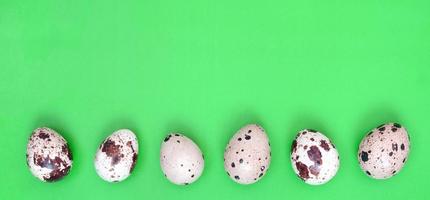 Quail eggs on a light green surface, top view, empty place for t photo