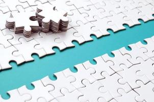 The blue path is laid on the platform of a white folded jigsaw puzzle. The missing elements of the puzzle are stacked nearby. Texture image with space for text photo